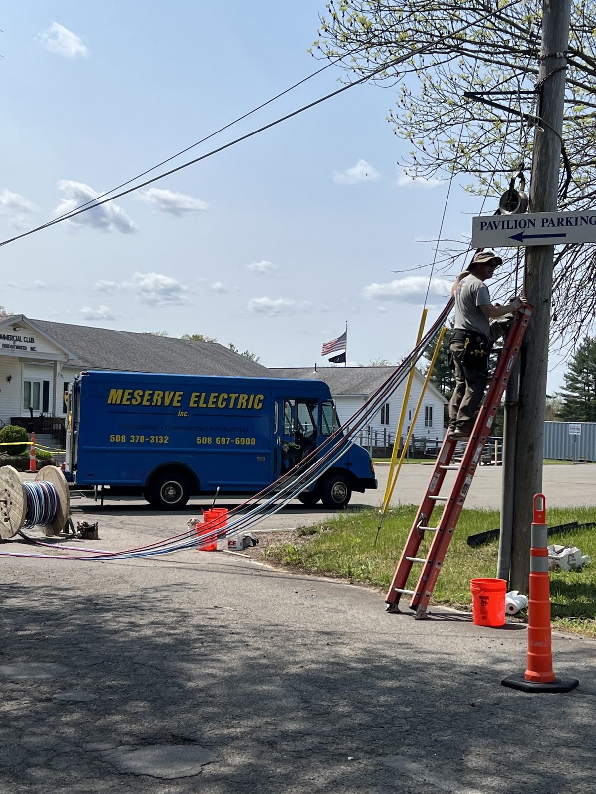 The Meserve Electric box truck on a job, with a crew member on a ladder and wire on the ground